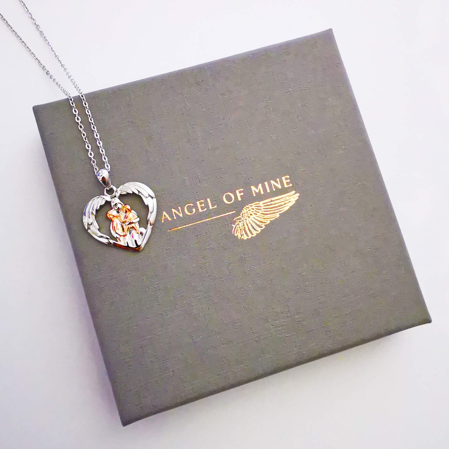 Sterling silver and rose gold pendant necklace. Depicts mum hugging two children under wings. Gift for mum.